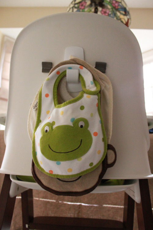 Stick a Command hook on the back of a high chair to hold bibs.